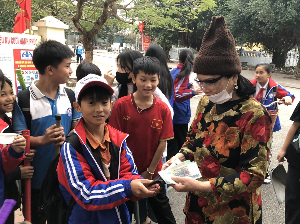 Em Nguyễn Văn Khôi, lớp 6E, trường THCS Hà An, trao trả lại chiếc túi và toàn bộ số tiền cho bà Vũ Thị Nhặt.