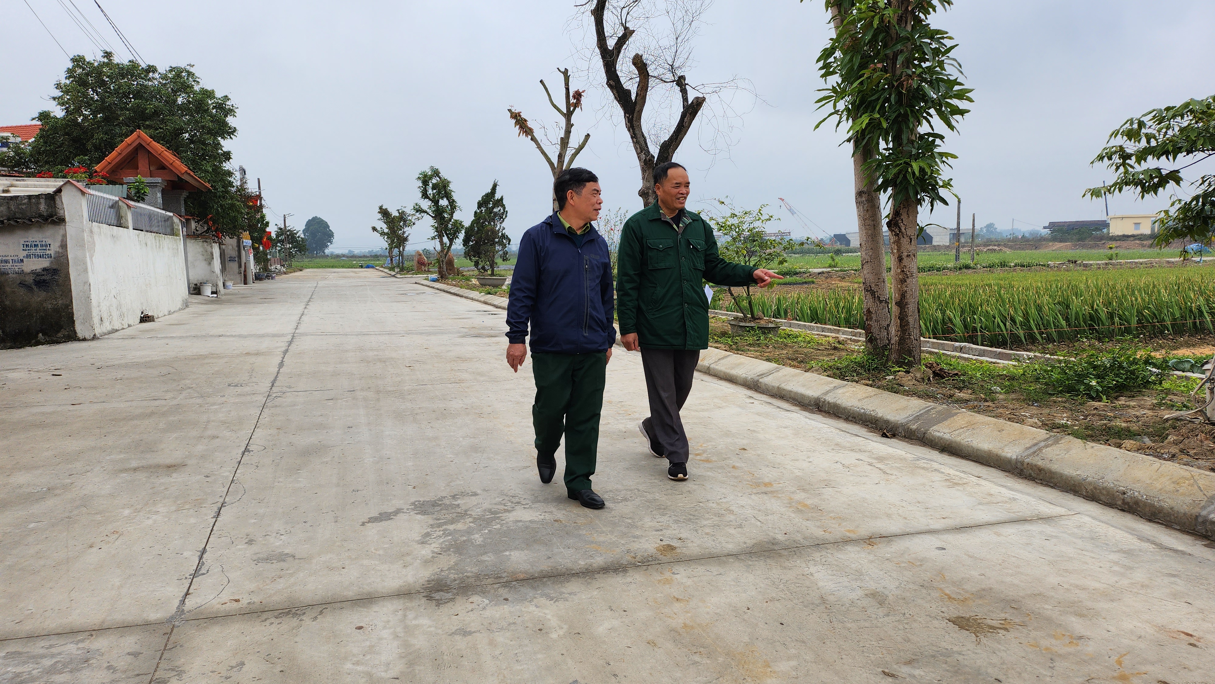 Đồng chí Nguyễn Mạnh Ngát (phải) phấn khởi chia sẻ về tuyến đường nội đồng trong khu phố được xây sửa rộng đẹp nhờ hưởng ứng tích cực của nhân dân.