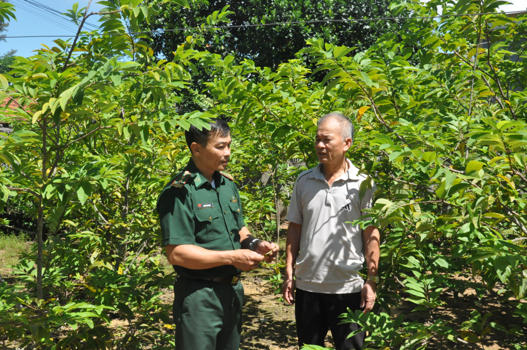 Trung tá Phạm Xuân Mạnh trao đổi với người dân về việc thực hiện các vườn mẫu trong xây dựng nông thôn mới ở địa phương