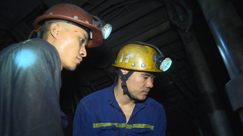 Thợ lò Phạm Đình Duẩn (bên phải) hướng dẫn công nhân mới khai thác than.