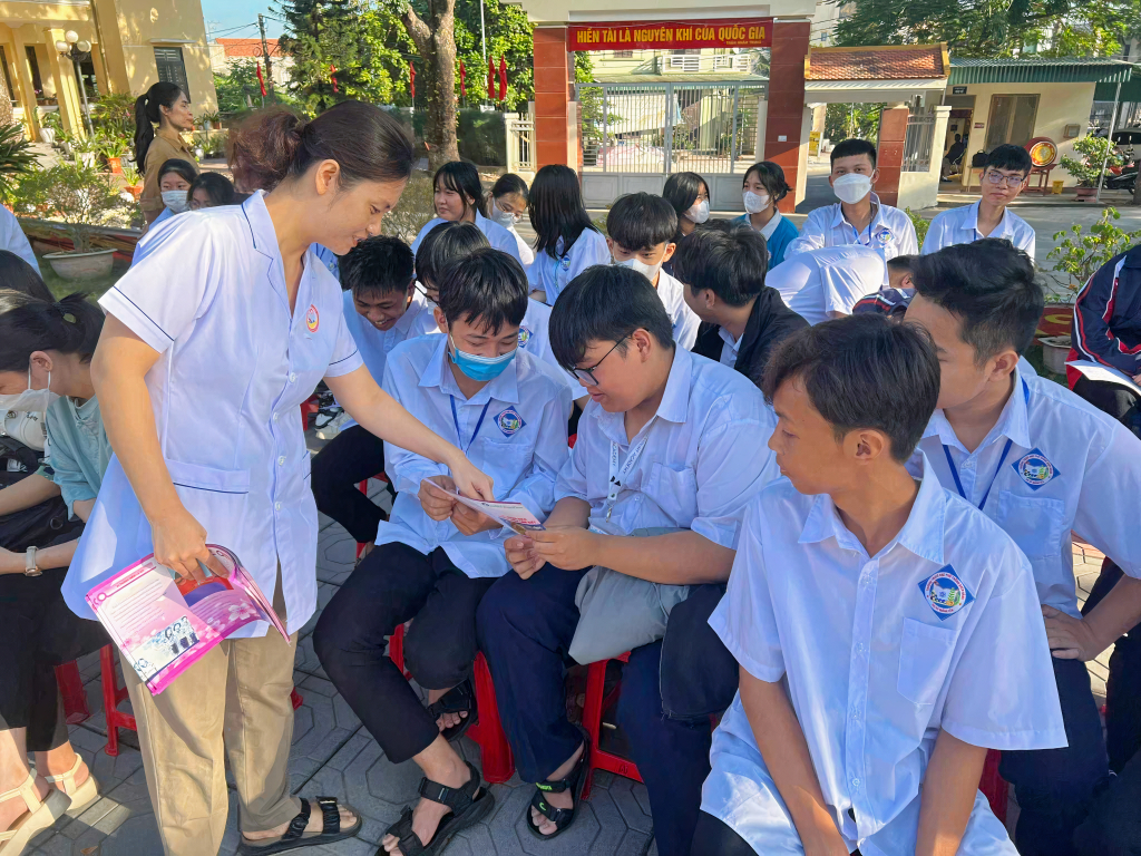 Cán bộ dân số phường Quảng Yên phát tờ rơi tuyên truyền cho học sinh phương pháp chăm sóc SKSS lứa tuổi vị thành niên, thanh niên.