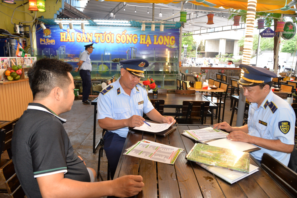 Cán bộ Đội QLTT số 5 tuyên truyền các quy định của pháp luật cho chủ một nhà hàng ăn uống tại khu du lịch Bãi Cháy, TP Hạ Long