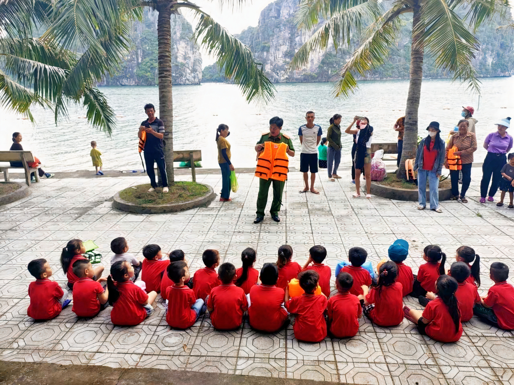 Công an xã Thắng Lợi hướng dẫn trẻ em trên địa bàn cách mặc áo phao. Ảnh: Quyền Hưng (CTV)