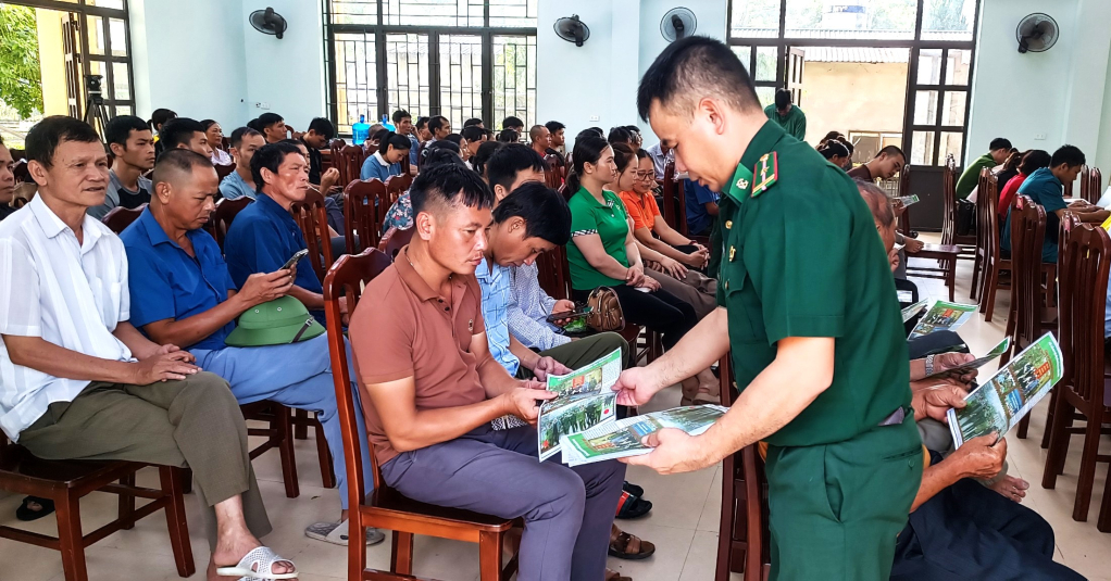 Cán bộ Đồn Biên phòng cửa khẩu Hoành Mô phát tờ rơi cho nhân dân xã Vô Ngại.