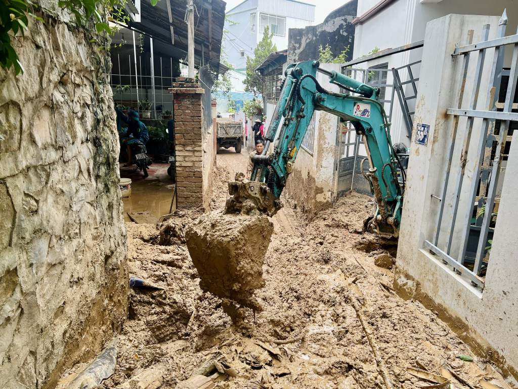 Máy xúc dọn dẹp trong khu vực ngõ nhỏ, bùn đất ngập cao.