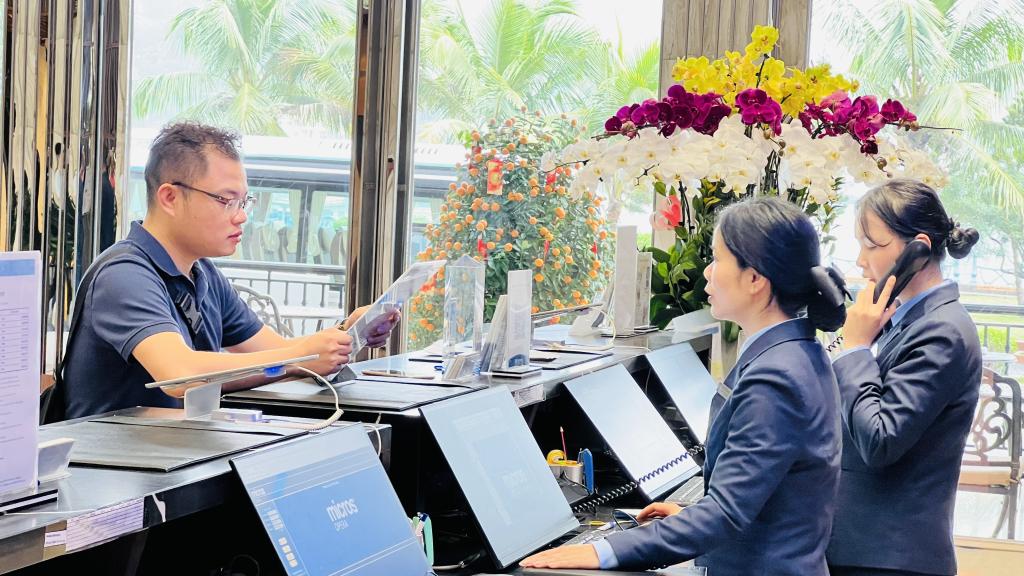 Người lao động ngành du lịch - dịch vụ đa số làm xuyên Tết. (Trong ảnh: Lễ tân khách sạn Whymham tiếp khách những ngày tết).