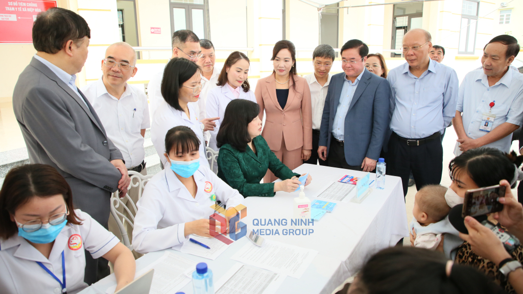 Bộ trưởng Bộ Y tế Đào Hồng Lan kiểm tra sổ tiêm chủng tại khu vực đón tiếp trẻ đến tiêm vắc-xin sởi tại Trạm Y tế xã Hiệp Hoà (TX Quảng Yên). Ảnh: Minh Hà