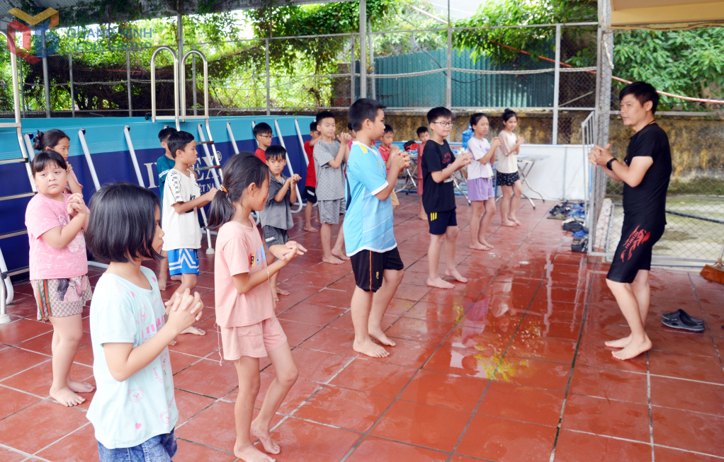 Các em học sinh có hoàn cảnh khó khăn Trường Tiểu học Phong Hải (TX Quảng Yên) tham gia lớp học bơi miễn phí được giáo viên dạy bơi hướng dẫn thực hiện các động tác khởi động trước khi học kỹ năng bơi trong bể.