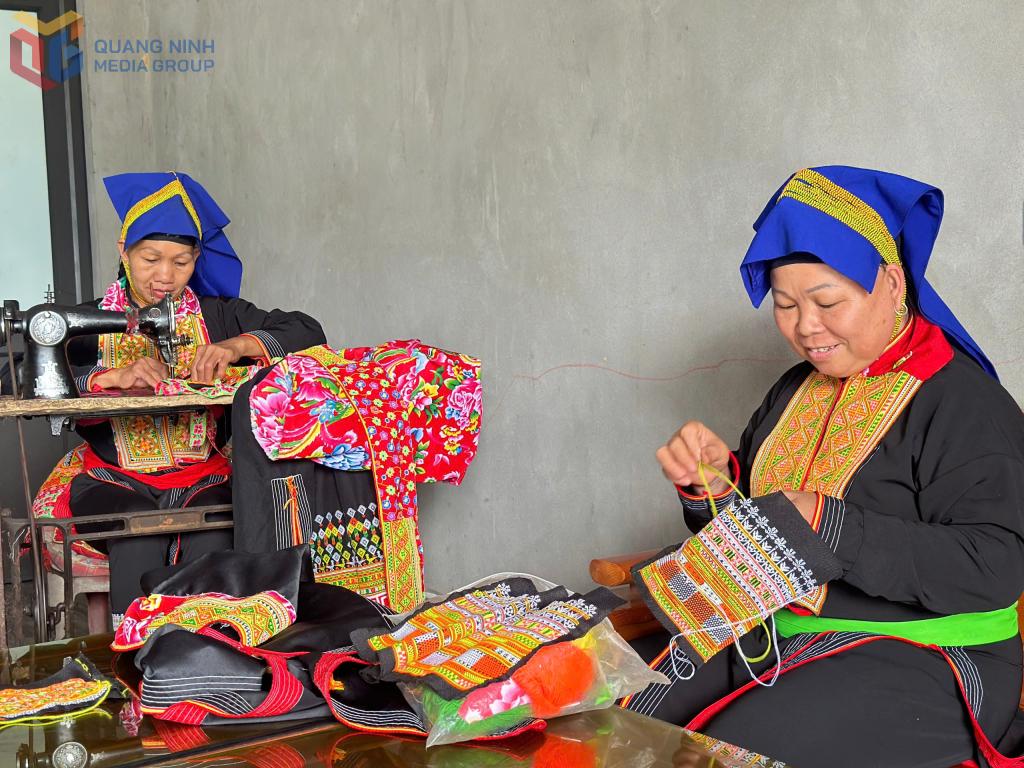 Bà Bàn Thị Xuân (bên trái), cùng phụ nữ xã Đồn Đạc, huyện Ba Chẽ giữ nghề may thêu trang phục truyền thống dân tộc Dao. Ảnh: Hùng Sơn