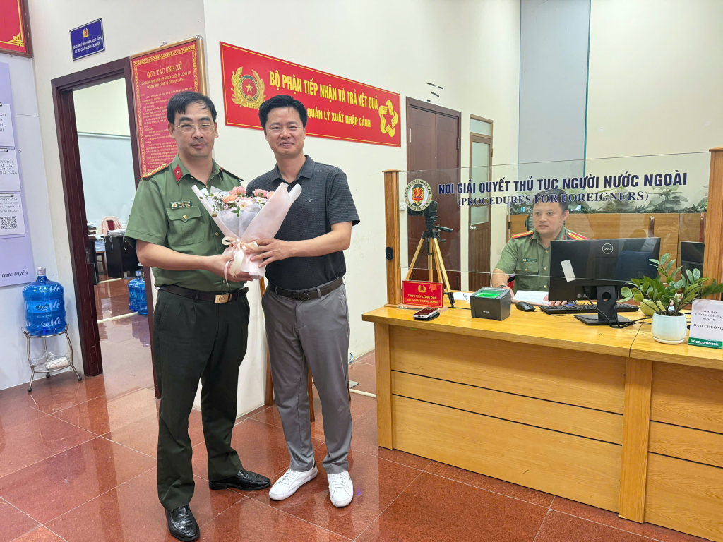Lãnh đạo Phòng Quản lý xuất nhập cảnh tặng hoa cho người nước ngoài đầu tiên được thu nhận hồ sơ định danh điện tử cấp độ 2.