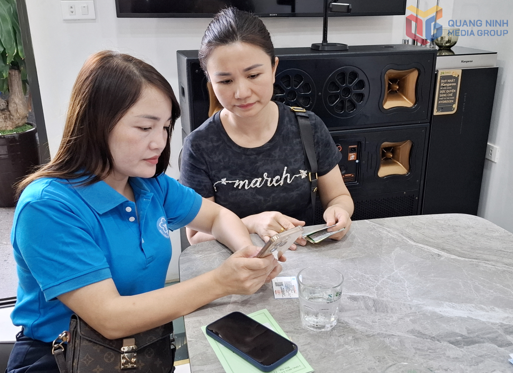 Cán bộ BHXH tỉnh đang giúp cập nhật BHYT tại ứng dụng VssID trên điện thoại thông minh cho chị Nguyễn Thị Hải Yến (phường Việt Hưng).