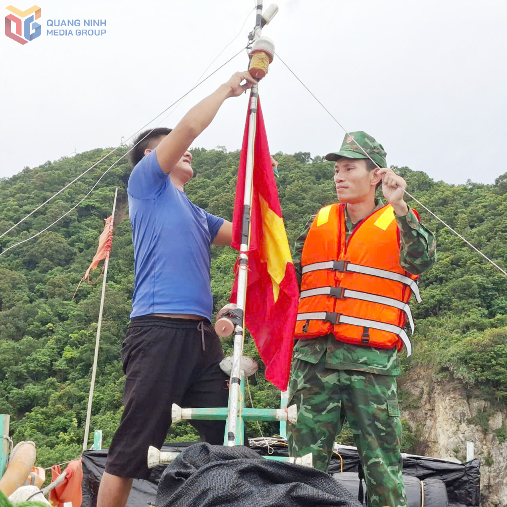 Cán bộ Đồn Biên phòng Đảo Trần giúp ngư dân treo cờ Tổ quốc. (Ảnh: Đồn BP Đảo Trần)