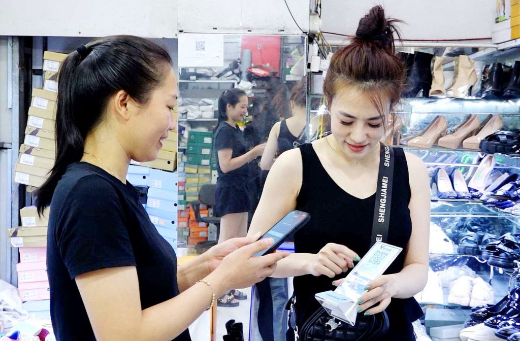 Người mua và người bán thực hiện giao dịch không dùng tiền mặt qua mã QR code tại chợ Cẩm Đông (TP Cẩm Phả). Ảnh: Song Hà